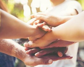Verschiedene Hände, die übereinander gestapelt sind, symbolisieren Zusammenarbeit und Gemeinschaft.
