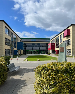 Blick auf das Forum Technik mit modernen Gebäuden und einem gepflegten Innenhof, umgeben von Büschen und Bänken.