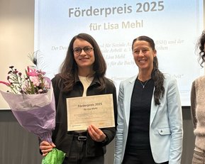 Lisa Mehl hält eine Urkunde für den Förderpreis 2025 und einen Blumenstrauß. Neben ihr steht eine weitere Person in formeller Kleidung.
